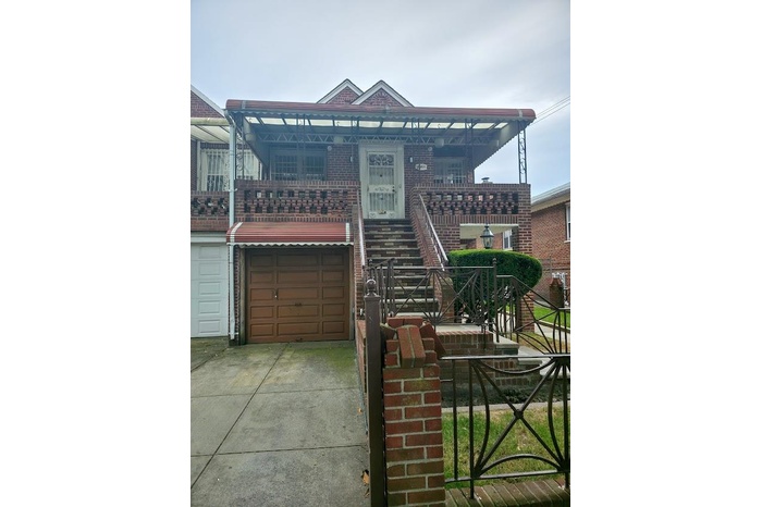View of front facade with concrete driveway, an attached garage, brick siding, and a balcony