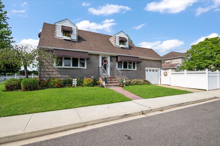 Cape cod home with a garage, a shingled roof, and concrete driveway