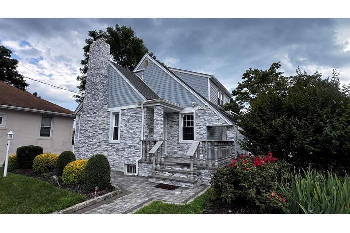 View of front of home featuring stone siding and a chimney