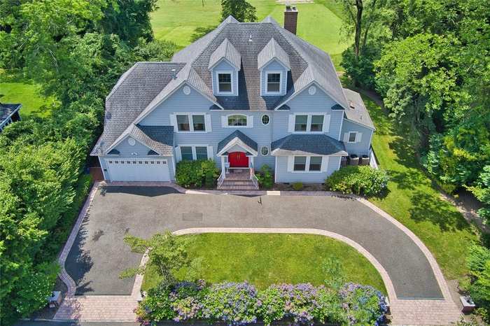 View of front facade with a garage, a shingled roof, a chimney, and asphalt driveway