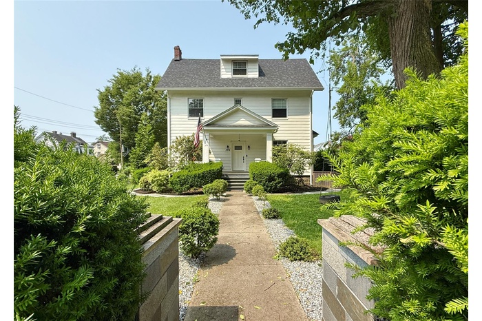 Traditional style home with a chimney and roof with shingles