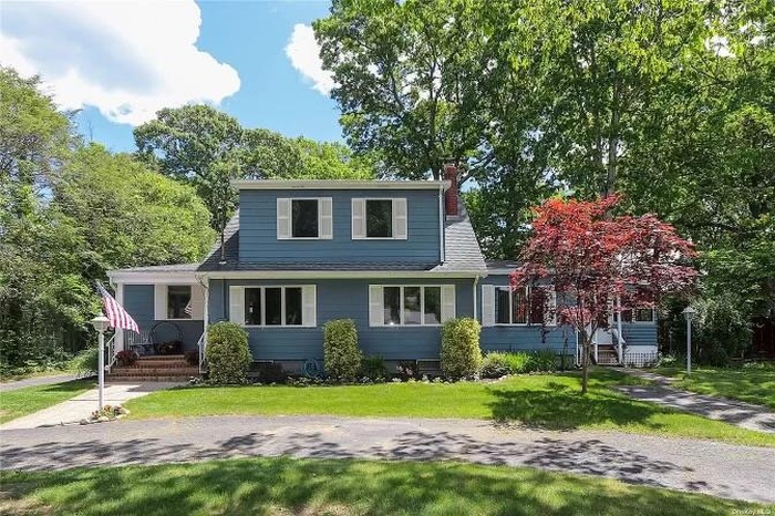 Traditional-style home with a front lawn, a chimney, and roof with shingles