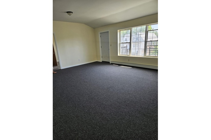 Unfurnished room with a baseboard heating unit and dark colored carpet