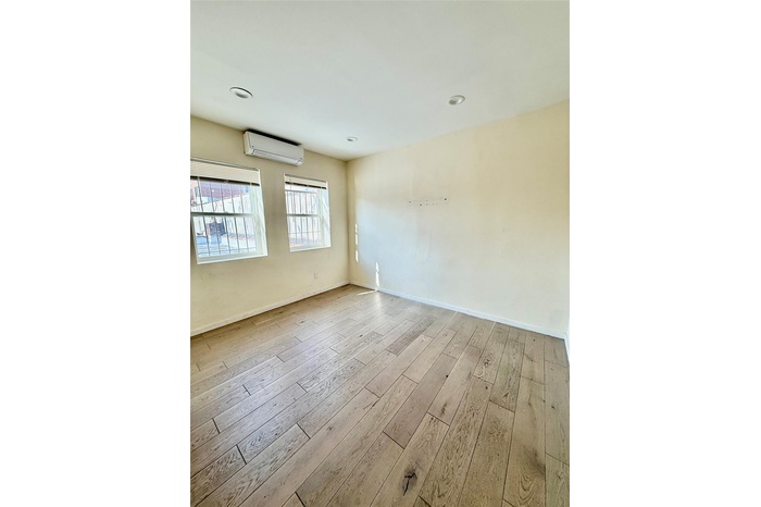 Unfurnished room with wood-type flooring, a wall mounted AC, and recessed lighting