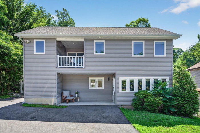 View of front facade featuring a balcony and asphalt driveway