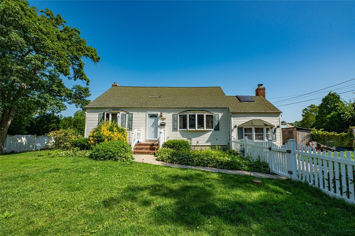 Cape cod-style house featuring a chimney, a fenced backyard, and a storage shed