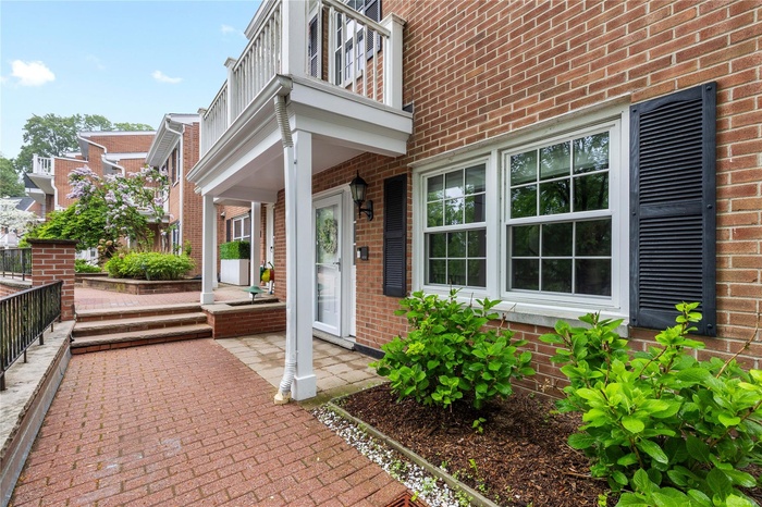 Entrance to property with a porch, brick siding, and a balcony