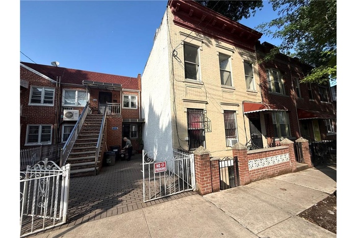View of building exterior with a fenced front yard and stairs