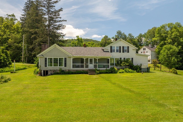 View of front of house with a chimney, a front lawn, and a sunroom