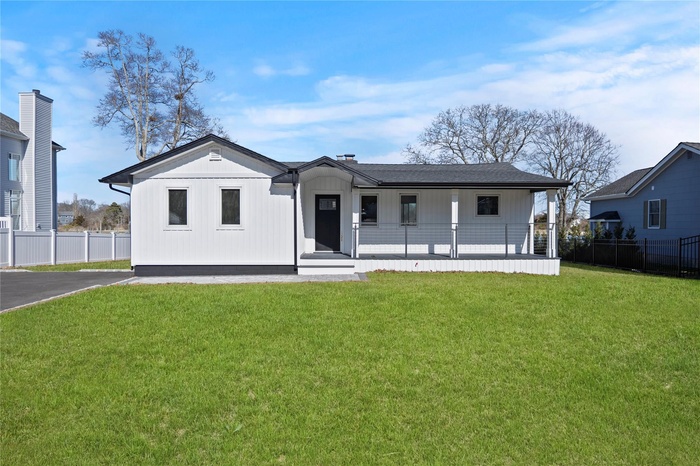 View of front facade featuring board and batten siding, a front lawn, fence, and covered porch