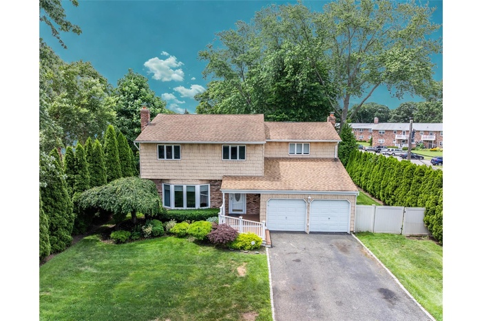 View of front of house with a chimney, a shingled roof, asphalt driveway, and an attached garage