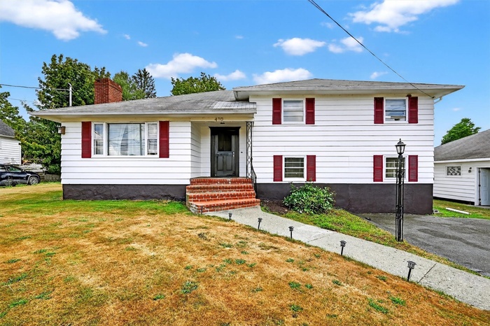 Tri-level home featuring a front yard, a chimney, and entry steps