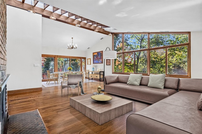 Living area featuring a chandelier, wood finished floors, beam ceiling, a fireplace, and high vaulted ceiling