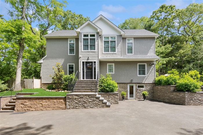 View of front of house with stone siding and front stairs.