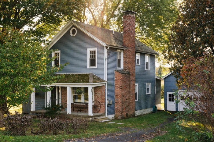 View of front of home with a chimney, covered porch, a garage