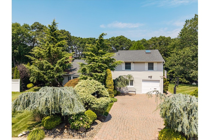 View of front of property with an attached garage, decorative driveway, and a shingled roof