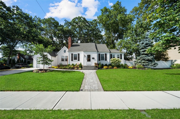 View of front of property with concrete driveway, a chimney, and a garage