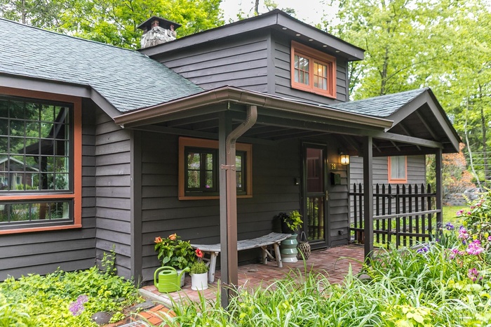 View of exterior entry featuring a chimney, a shingled roof, and a porch