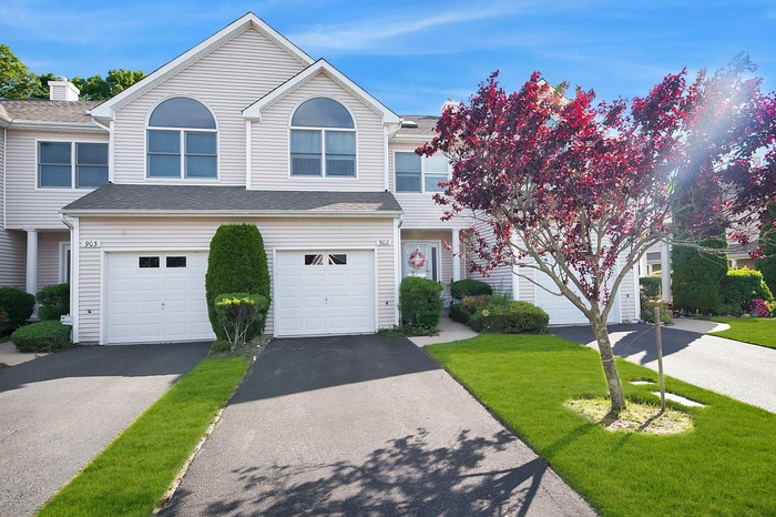 Traditional-style house featuring an attached garage, asphalt driveway, a front yard, and roof with shingles