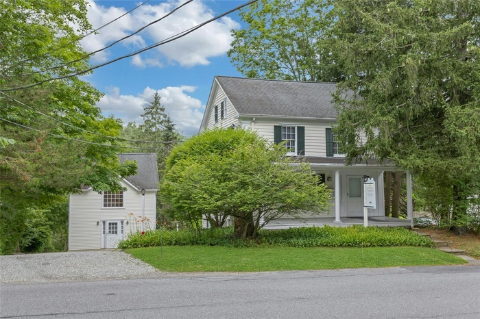 View of front of property featuring covered porch, a front yard, and roof with shingles