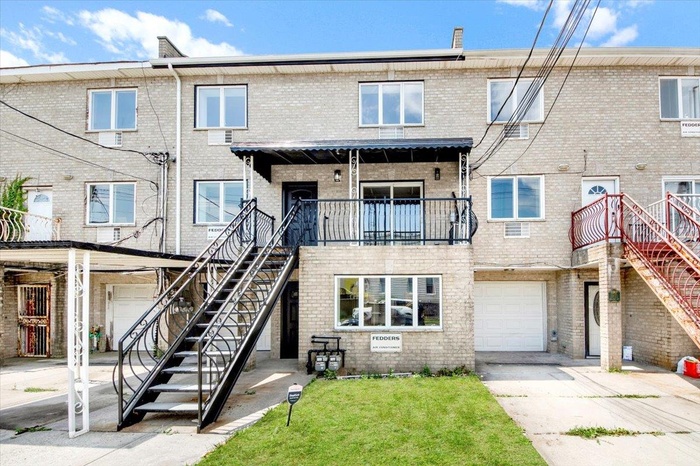 View of front of property featuring stairway, brick siding, driveway, an attached garage, and a front yard