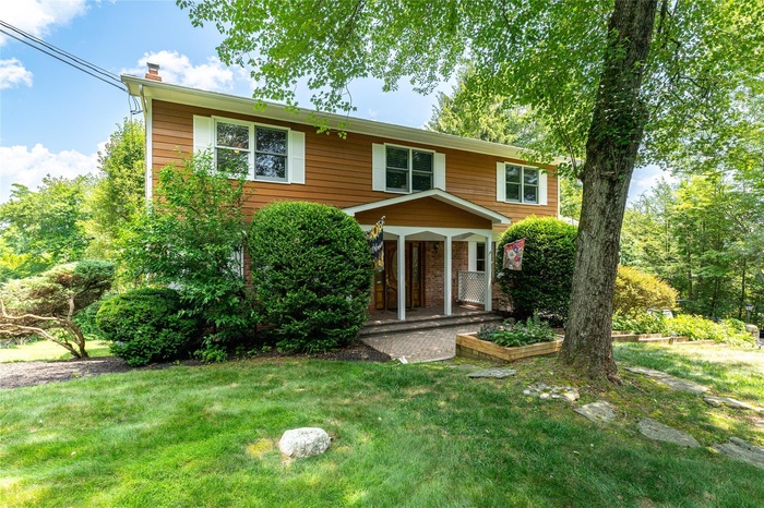 View of front of property featuring a front lawn, a chimney, a porch, and brick siding