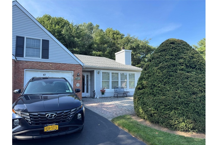 View of front of house with brick siding, a garage, a chimney, and a shingled roof