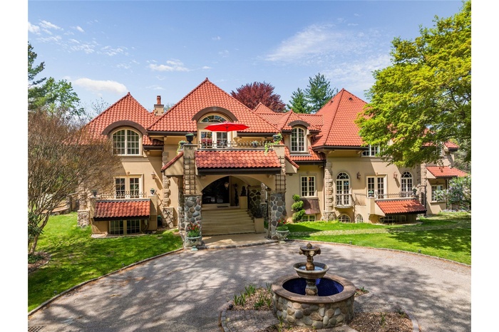 Front view of property with a balcony, stucco siding, and a clay tiled roof
