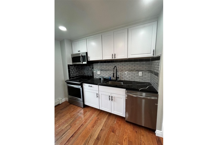 Kitchen with dishwasher, stove, light wood-style flooring, and white cabinets