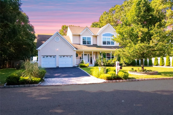 Traditional-style home featuring a porch, decorative driveway, and a garage