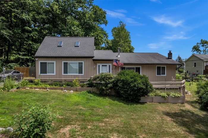 Back of house featuring a garden, a shingled roof, and a chimney