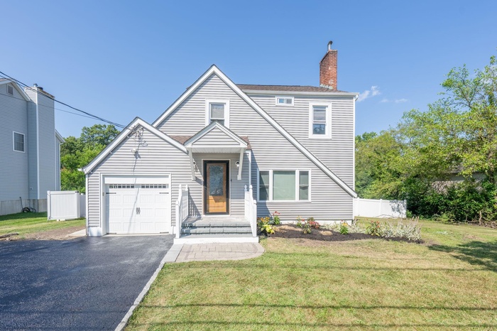View of front of house featuring driveway, an attached garage, and a chimney