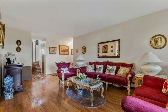 Living area with wood finished floors and a baseboard heating unit