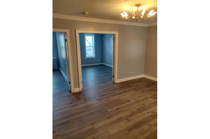 Unfurnished room featuring radiator, dark wood-style floors, a chandelier, and crown molding