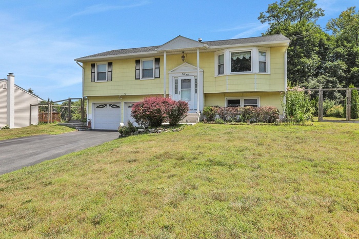 Raised ranch with an attached garage and asphalt driveway