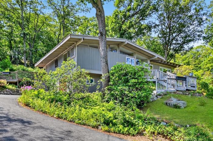 View of side of home with a deck and view of scattered trees