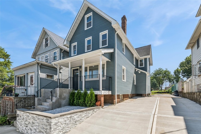 View of front of house with a porch, a chimney, concrete driveway, and a shingled roof
