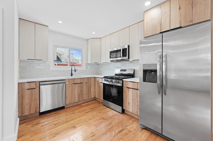 Kitchen featuring appliances with stainless steel finishes, light wood-type flooring, light countertops, recessed lighting, and tasteful backsplash