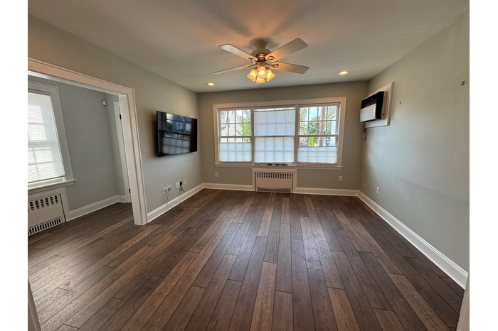Unfurnished room featuring a ceiling fan, radiator, dark wood finished floors, and recessed lighting