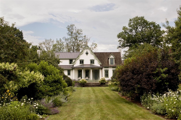 View of front of property with a chimney, a front yard, a metal roof, and a standing seam roof