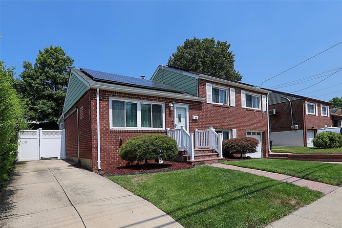 Split level home with brick siding, concrete driveway, solar panels, and an attached garage