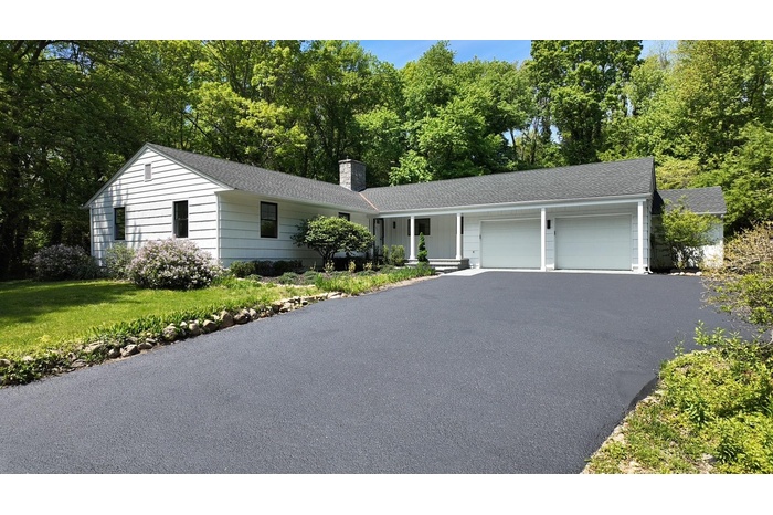 Single story home with driveway, an attached garage, a shingled roof, a chimney, and a front yard
