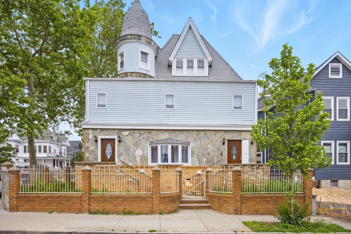 View of front of home with a gate, a fenced front yard, and stone siding