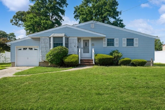 View of front of house with a front yard, driveway, and a garage