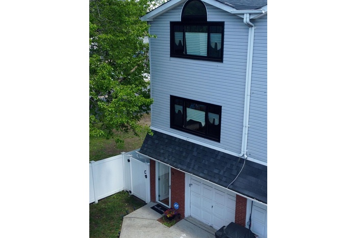 View of front of home featuring a garage, a shingled roof, and brick siding