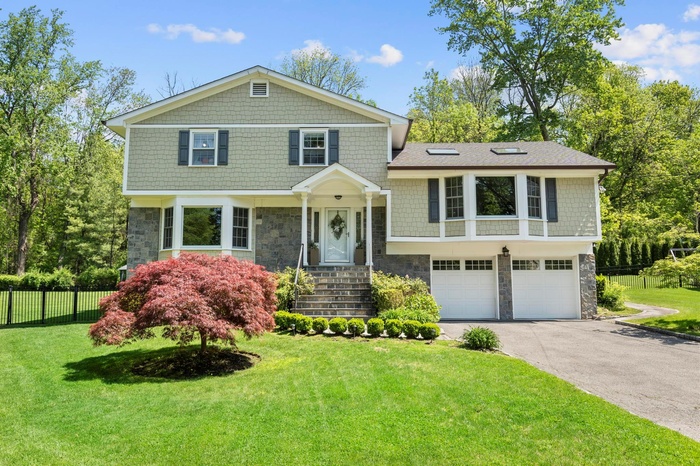View of front of house featuring stone siding, asphalt driveway, and a garage