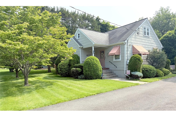 CapeCod-style home featuring a front lawn and a shingled roof