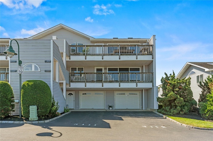 Rear view of property with driveway, a garage, and a balcony