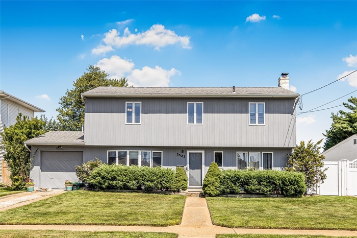 Colonial home with an attached garage, a chimney, roof with shingles, and concrete driveway