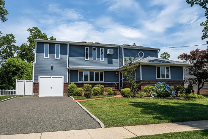 View of front of property with brick siding, an attached garage, asphalt driveway, and a chimney